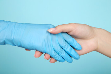 Doctor and patient shaking hands on blue background