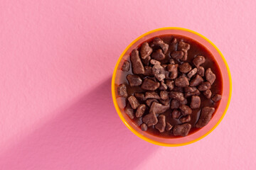 acrylic cup with brigadeiro and chocolate sprinkles on pink background