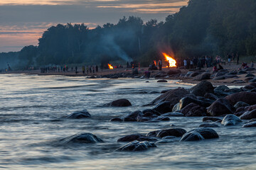 Unrecognisable people celebrating summer solstice with large bonfires on Baltic Sea sandy beach