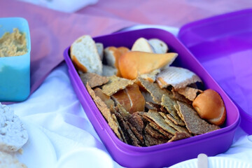 Box of bread and homemade crackers, served on a picnic blanket. Selective focus.