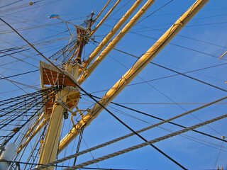 Masts of a sailing ship seen from below against the blue sky