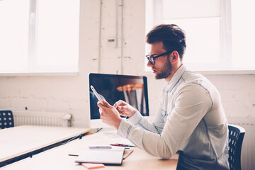 Concentrated male IT developer making setting in new application on mobile updating software, young...