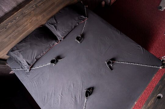 Bedroom For Intimate Meetings. VDSM Equipment And Sex Toys. Leather Handcuffs With A Chain On A Gray Sheet. Fifty Shades Of Gray. Fetish Domination.