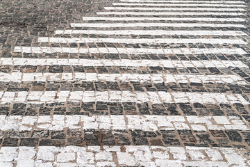Street paving road markings with a pedestrian crossing. Abstract background of paving stones. Cobblestone pavement.