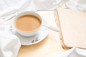 Cup of cappuccino standing on a book and a white sheet