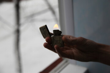 Hand holding a lighter with fire