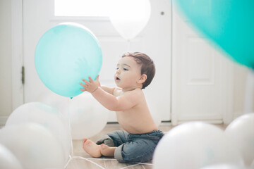 Fototapeta na wymiar baby playing with balloons white and blue 