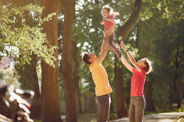 Obraz premium Family with cute little daughter. Father in a yellow t-shirt. People walks in a park.