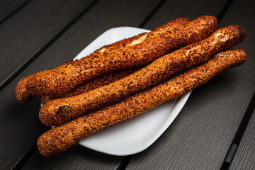 Crispy breadsticks (grissini) with sesame seeds on a white plate