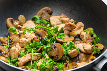 turkey meat with mushrooms and rocket in frying pan