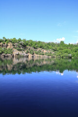 Naklejka premium Beautiful river in the highlands in summer. Lake in an ecologically clean park reserve on a background of hills. A pretty landscape in the spring. Stock photo for design