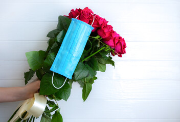 Medical mask on the beautiful flowers. Safe present during the quarantine time. Stay at home concept. Bouquets delivery.