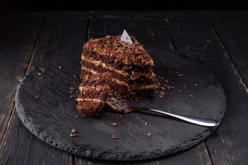 A piece of broken cake. A slice of bitten cake. Chocolate cake with powder.