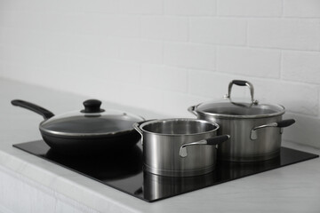 Saucepots and frying pan on induction stove in kitchen