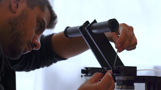 Man assambling 3d printer at home