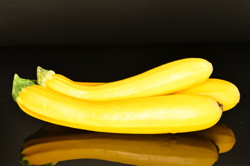 Fresh ripe, bright yellow zucchini, close-up, on a black background.
