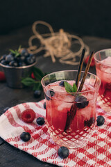 two Glass of cold red alcohol cocktail decorated with ice, fruit, flowers and mint on table at the bar