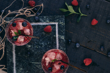 two Glass of cold red alcohol cocktail decorated with ice, fruit