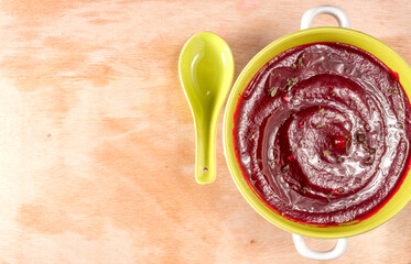Beetroot soup in a bowl on a wood table. Top view. Copy space at right