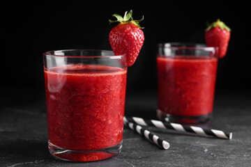 Tasty strawberry smoothie in glass on black table