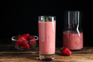 Tasty strawberry smoothie with mint in glass on wooden table