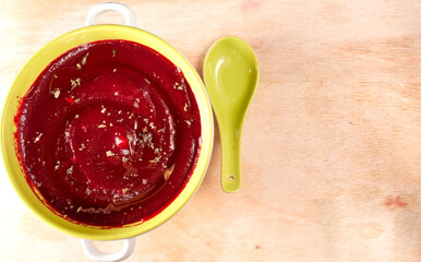 Beetroot soup in a bowl on a wood table. Top view. Copy space at right