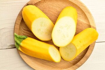 Fresh ripe, bright yellow zucchini, close-up, on a round wooden tray .