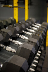 Obraz premium Black dumbbell set in the gym. Close up many metal dumbbells on rack in sport fitness center. Weight Training Equipment concept.