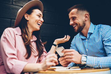 Cheerful male and female friends enjoying free time together joking and share multimedia in...