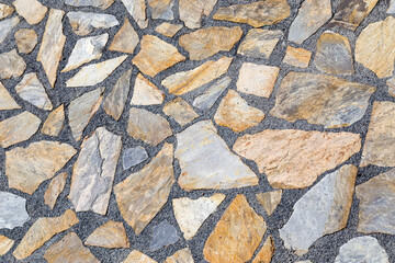 Concrete surface with large colored stones on the sand, stonewall
