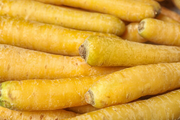 Many raw yellow carrots as background, closeup