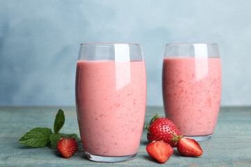 Tasty strawberry smoothies in glasses on blue wooden table