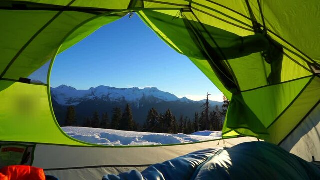 Lockdown shot of sleeping bag in green tent on snow against blue sky during sunny day - Elfin Lakes, British Columbia