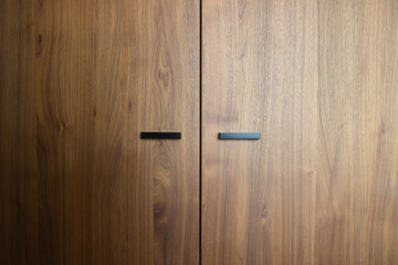 Beautiful brown wooden oak doors of a cabinet with black modern handles modern background texture