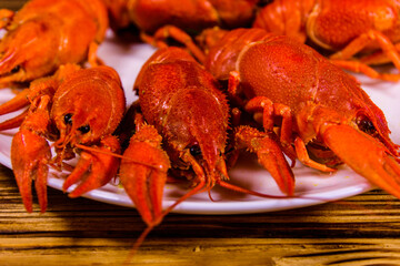 Plate with boiled crayfishes on wooden table