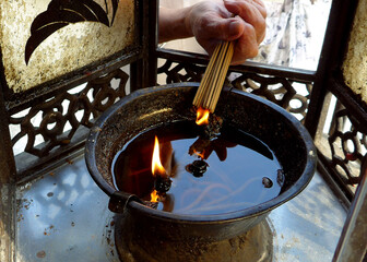 An old lady's hand is lighting before praying in a temple.