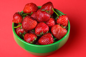 strawberries in green bowl on red background