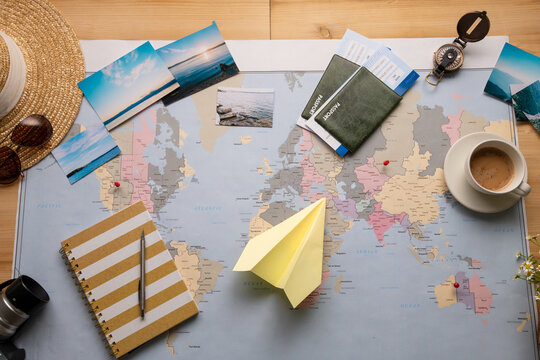 Above view of world map with scenic photographs, paper plane, diary, coffee cup and passports