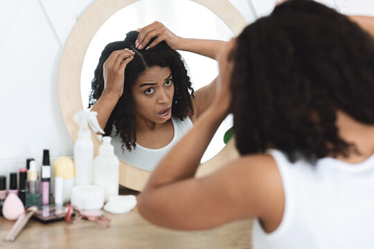 Dandruff Problem. Sad Black Woman Looking At Her Hair Roots In Mirror