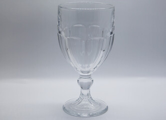 Cup with colorless glass feet and sculpted details, cylindrical and transparent, exquisite utensil used to retain and serve liquids, it is generally wider in the mouth, used in decorations and parties