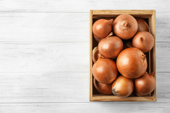 Ripe Yellow Onion Bulbs In Crate On White Wooden Table, Top View. Space For Text