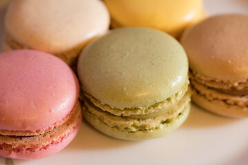 A close-up of pastel-coloured macarons indoors against a soft neutral background.
