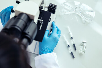 Female scientist uses microscope. Female scientist in protective gloves uses medical microscope...