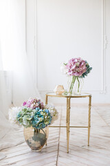 Tender simple  interior in light colors with tule, bouquets of artificial hydrangea and elegant  mirror table on light parquet floor