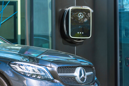 Black Mercedes-Benz three car store Mercedes, power supply plugged into. Electric car charging on parking lot with electric car charging station on city street.. Russia, Saint-Petersburg. 14 may 2020.