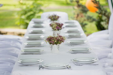 A festive table setting with beautiful bouquets of field wild flowers outdoors. Celebrating of Birthday or wedding outdoor. Party