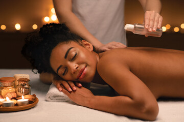 Fototapeta na wymiar Relaxed african woman enjoying aromatherapy and massage at spa