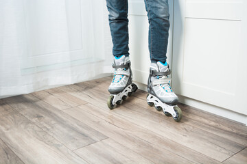 Two legs with jeans in roller skates standing at home on floor. Woman doing active sport at home in new equipment. Copy space