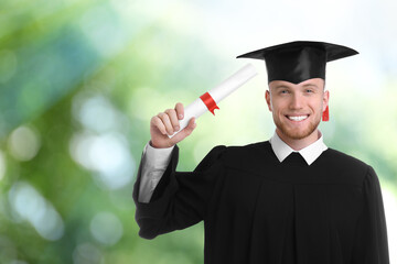 Happy student with graduation hat and diploma on blurred background, space for text