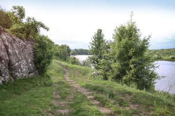 Nice mountain road with a beautiful view. A rock on the side of a dirt path. Stock landscape for design